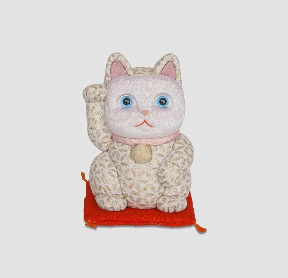 White kimekomi lucky cat with a raised paw on a red cushion